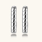 Close-up of platinum-plated sterling silver hoop earrings with horizontal textured grooves on white background.