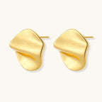 Close-up of organic gold-plated sterling silver stud earrings with flowing sculptural design and curved cut-outs