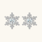 Sterling silver snowflake stud earrings with brilliant moissanite centers and intricate geometric patterns on cream background
