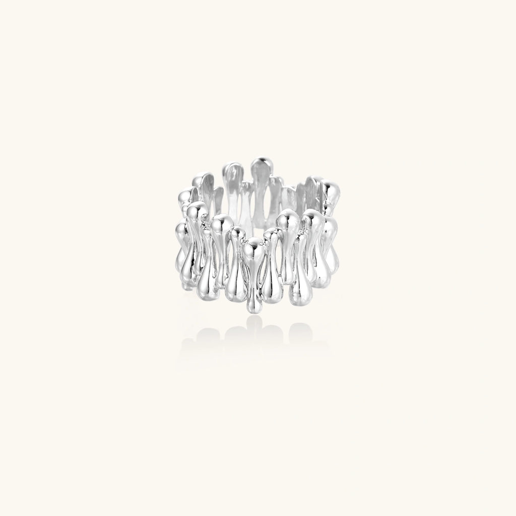 Wide band ring with sculptural wave ripples in polished white gold plated eco-brass on cream background