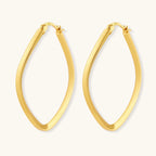 Set of geometric gold-plated sterling silver hoop earrings in oval and cushion shapes on cream background