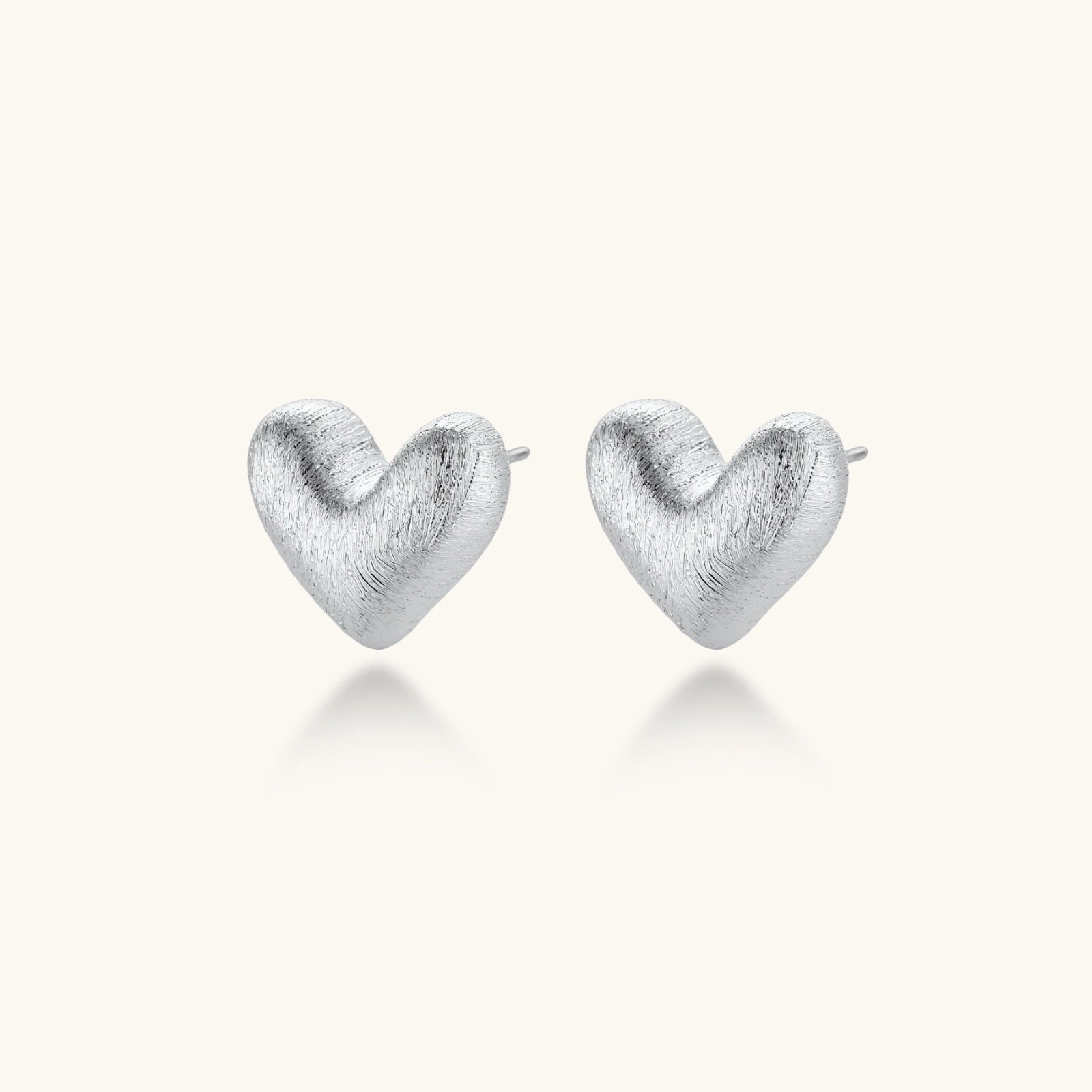 Pair of small heart-shaped stud earrings with brushed metallic finish, showing both silver and gold variants on neutral background.