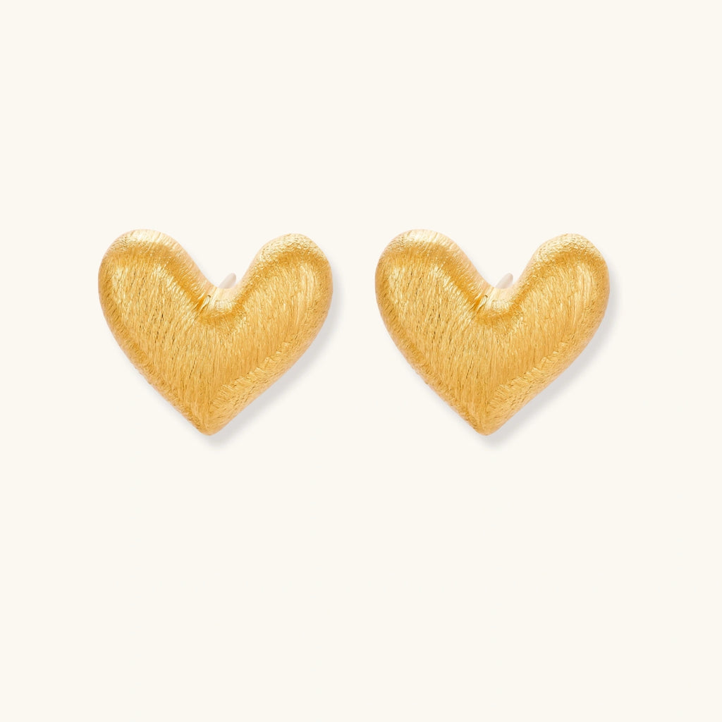 Pair of small heart-shaped stud earrings with brushed metallic finish, showing both silver and gold variants on neutral background.
