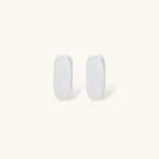 Pair of small silver-plated huggie hoop earrings with clean minimal design on neutral background.